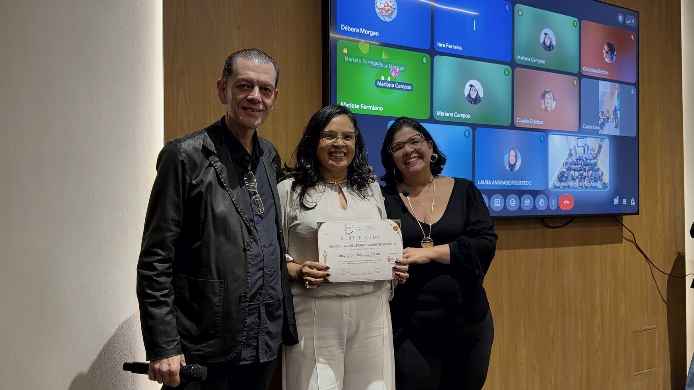Ju Andrade, psicanalista clínica formada pelo IUPC, segurando o certificado de conclusão